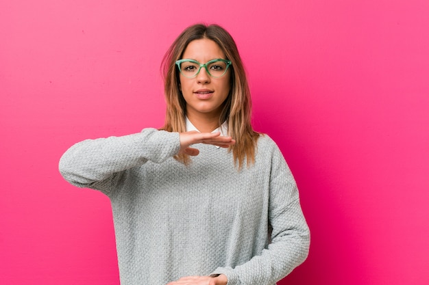 Young authentic charismatic real people woman against a wall holding something with both hands, product presentation.