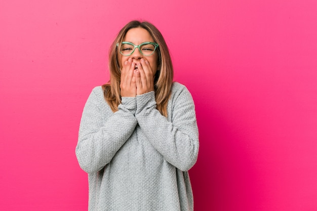 Young authentic charismatic real people woman against a wall laughing about something, covering mouth with hands.