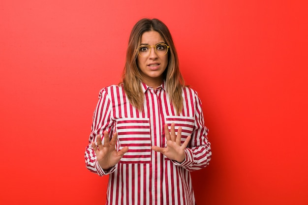 Young authentic charismatic real people woman against a wall rejecting someone showing a gesture of disgust.