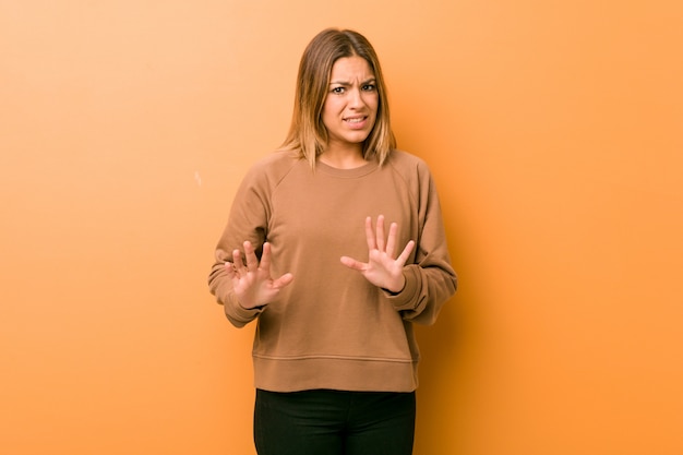 Young authentic charismatic real people woman against a wall rejecting someone showing a gesture of disgust.