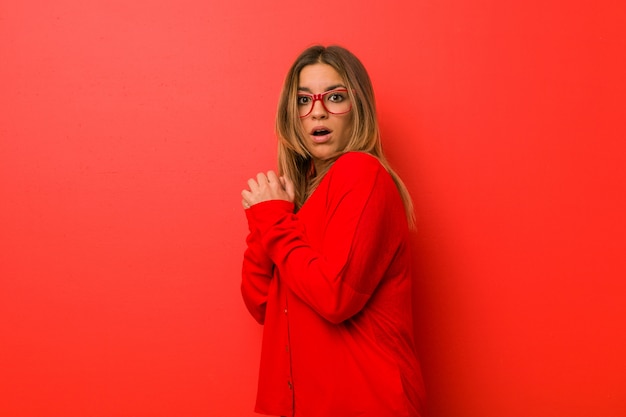 Young authentic charismatic real people woman against a wall scared and afraid.