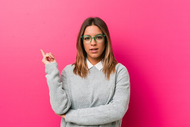 Young authentic charismatic real people woman against a wall smiling cheerfully pointing 