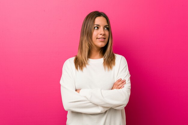 Young authentic charismatic real people woman against a wall smiling confident with crossed arms.