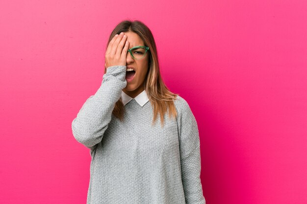 Young authentic charismatic  woman against a wall having fun covering half of face with palm.