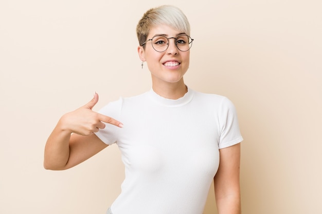 Young authentic natural woman wearing a white shirt person pointing by hand to a shirt copy space, proud and confident