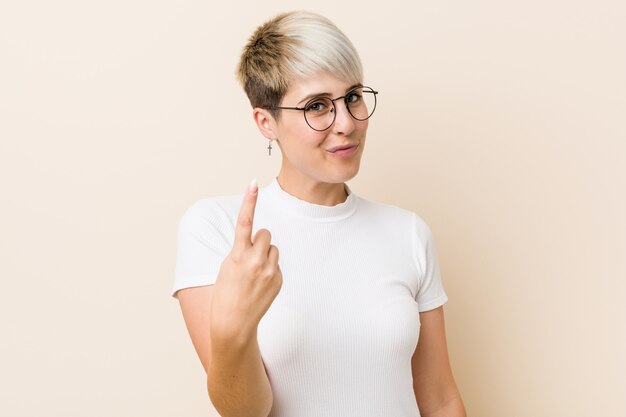 Young authentic natural woman wearing a white shirt pointing with finger at you as if inviting come closer.