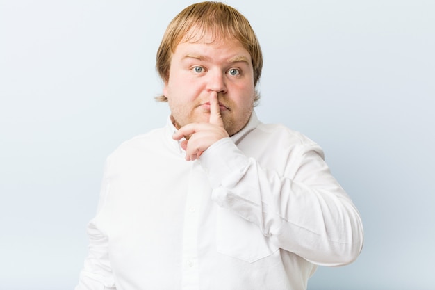 Young authentic redhead fat man keeping a secret or asking for silence.