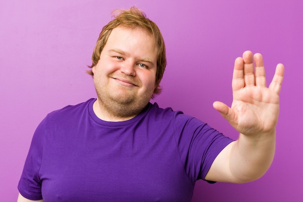 Young authentic redhead fat man standing with outstretched hand showing stop sign, preventing you.