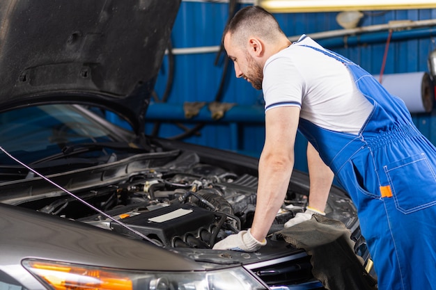 Young automechanic man repairing the car