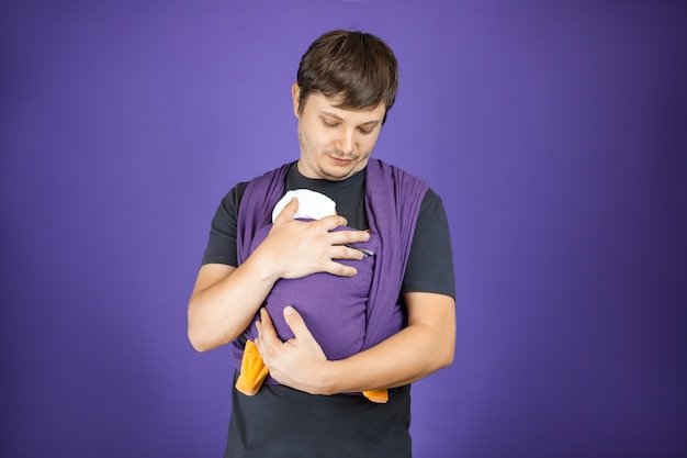 Young babywearing father and baby in sling front wrap cross carry hugs his baby