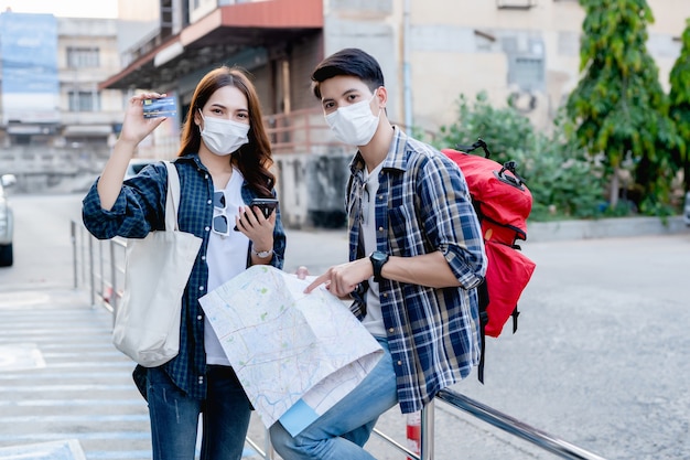 Young backpacker man holding paper map and pretty woman wear sombrero hold smartphone and showing credit card  in her hand, They use them to payment for trip  with happiness on vacation