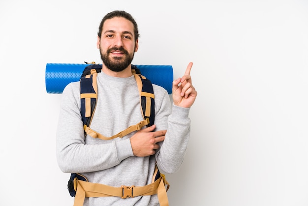 Young backpacker man isolated on a white wall smiling cheerfully pointing with forefinger away.