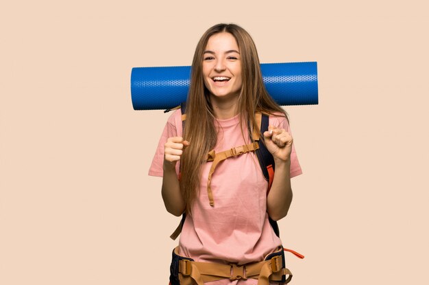 Young backpacker woman celebrating a victory in winner position on isolated yellow wall