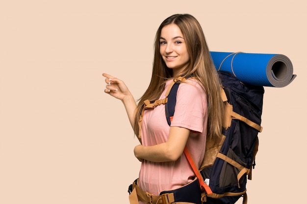 Young backpacker woman pointing finger to the side in lateral position