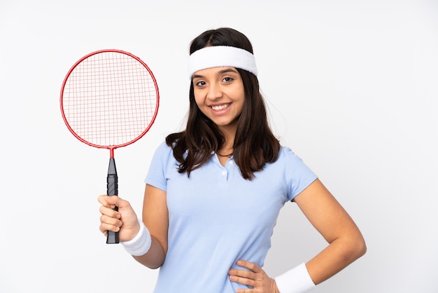 Young badminton player woman over isolated white background posing with arms at hip and smiling