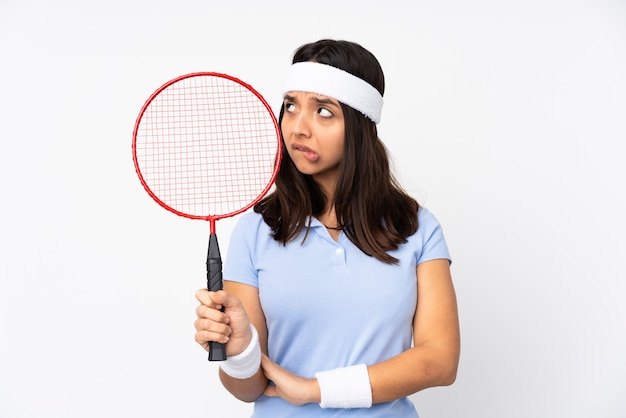 Young badminton player woman over isolated white wall with confuse face expression