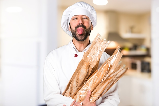 Foto giovane panettiere che tiene un po 'di pane e prende la lingua in cucina