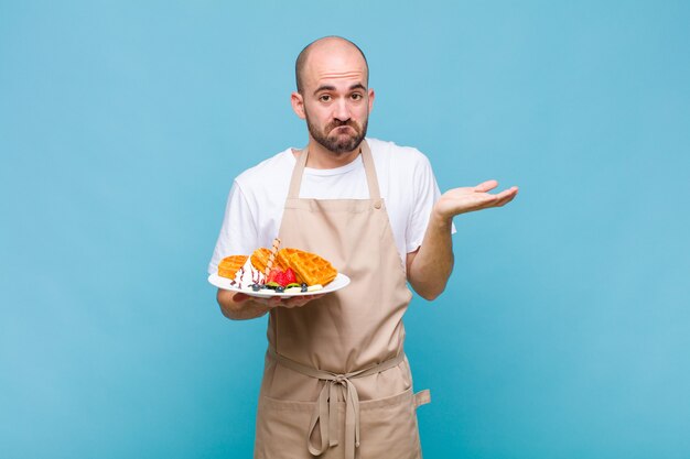 ワッフルを持つ若いパン屋の男