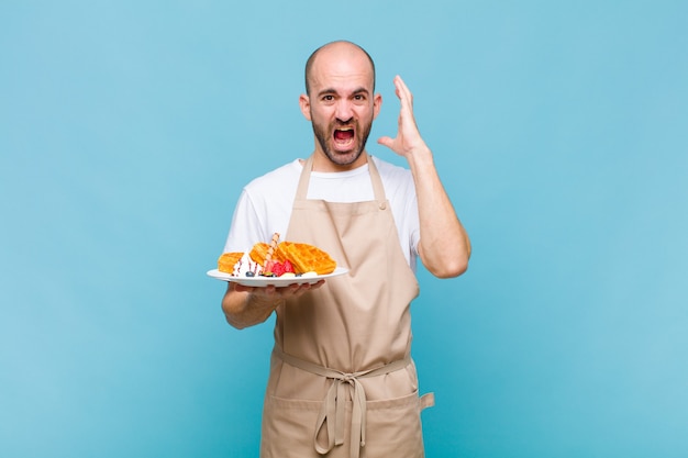 ワッフルを持つ若いパン屋の男