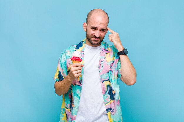 Young bald man feeling confused and puzzled, showing you are insane, crazy or out of your mind