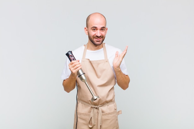 Giovane uomo calvo che si sente felice, sorpreso e allegro, sorridente con atteggiamento positivo, realizzando una soluzione o un'idea