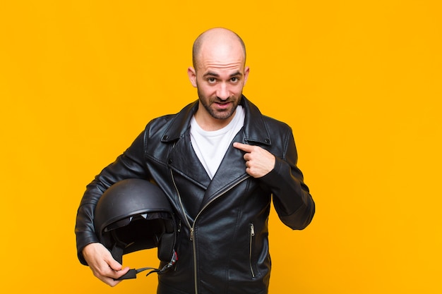 Young bald man feeling happy, surprised and proud, pointing to self with an excited, amazed look