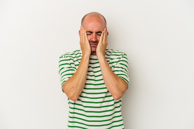 Young bald man isolated on white background crying, unhappy with something, agony and confusion concept.