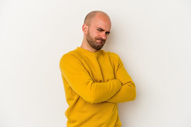 Young bald man isolated on white background frowning face in displeasure, keeps arms folded.