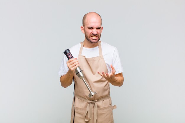 Young bald man looking angry, annoyed and frustrated screaming