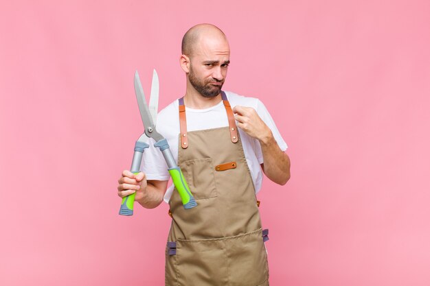 Young bald man looking arrogant, successful, positive and proud, pointing to self