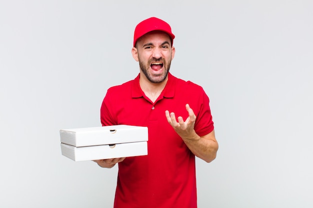 Young bald man looking desperate and frustrated, stressed, unhappy and annoyed, shouting and screaming