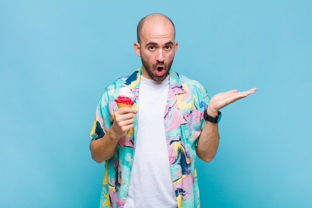 Young bald man looking surprised and shocked