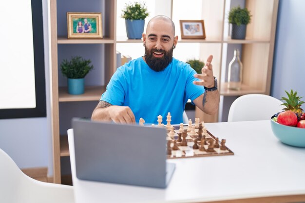 Photo young bald man playing online chess game sitting on table at home