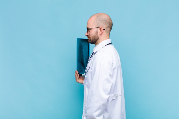 Young bald man on profile view looking to copy space ahead, thinking, imagining or daydreaming