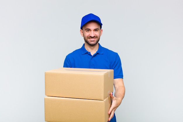 Young bald man smiling happily with friendly, confident, positive look, offering and showing an object or concept