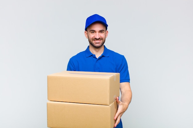 Young bald man smiling happily with friendly, confident, positive look, offering and showing an object or concept