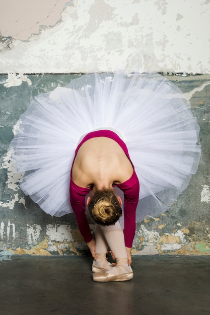 Young ballerina dancer dancing classical ballet against rustic wall