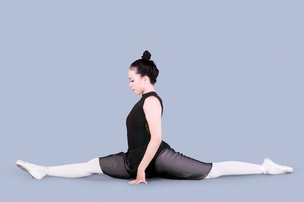 Young ballerina doing split exercise in the studio