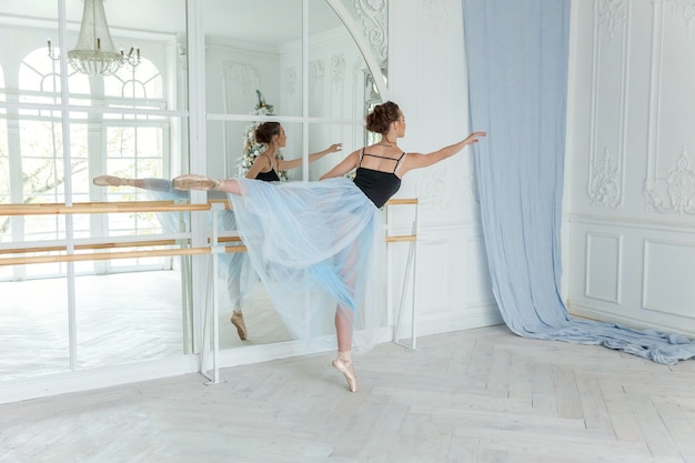 Young ballerina practicing ballet positions in studio