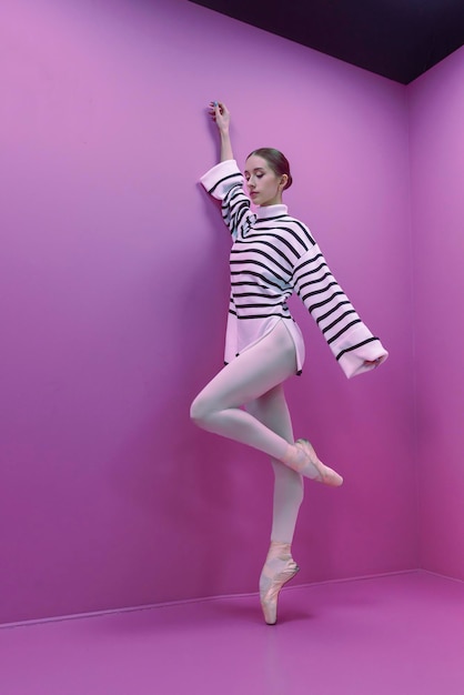 Young ballerina in white tights and a halfskirt poses ballet steps standing on pointe shoes