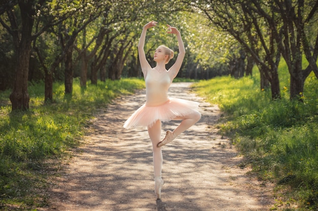 Young ballet dancer showing classic ballet poses outdoors at sunset