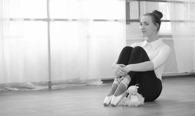 Young ballet dancer on a warm-up. The ballerina is preparing to perform in the studio. A girl in ballet clothes and shoes kneads by handrails.