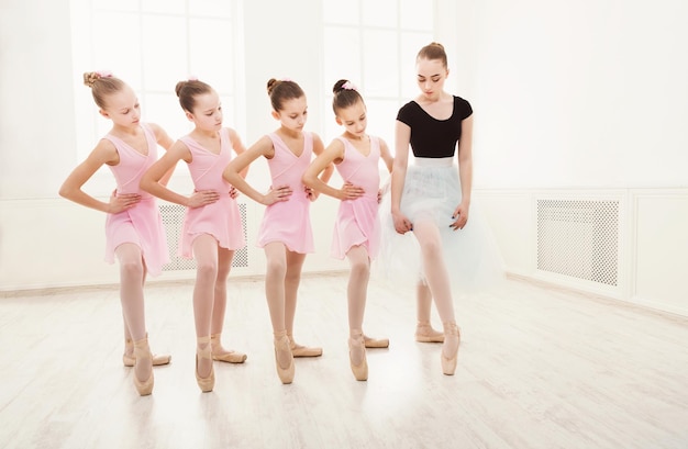 Photo young ballet teacher and students ballerinas in dance class. girls are engaged in choreography in the ballet school, copy space