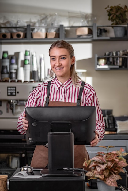 Foto giovane ragazza barista vicino a un registratore di cassa giovane barista che utilizza un moderno registratore di cassa al bancone del bar