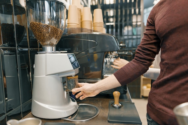 Young barista male preparing an espresso on coffee machine