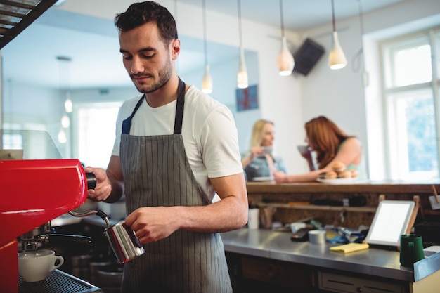 Young barista pouring coffee at cafe