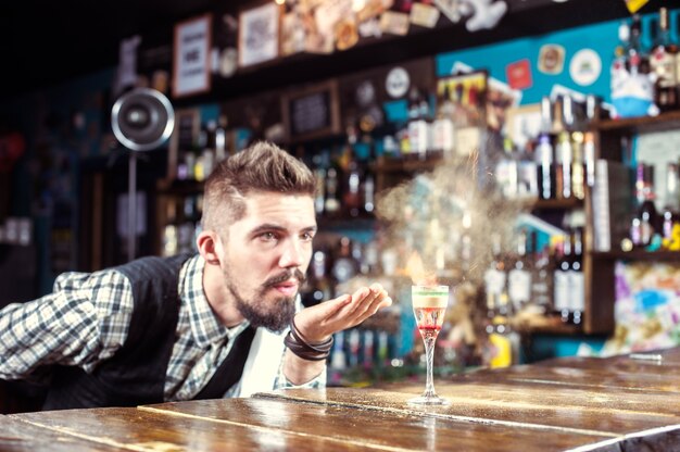 Young barman places the finishing touches on a drink in the night club