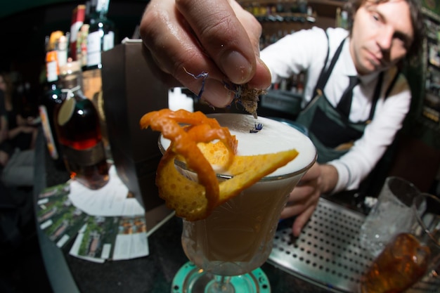 Photo young bartender making cocktail in counter