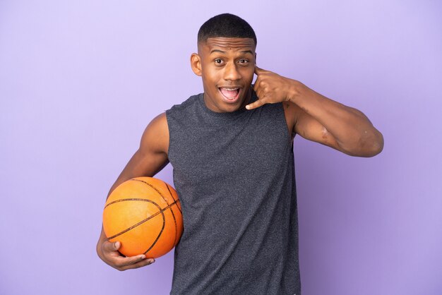 Young basketball latin player man isolated on purple wall making phone gesture. Call me back sign