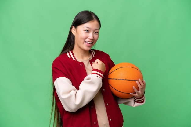 Young basketball player asian woman over isolated background celebrating a victory